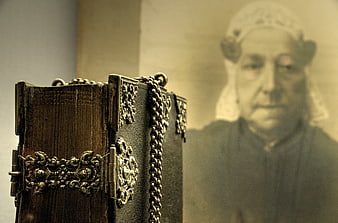 Antique leather book with silver clasps and blurred portrait background