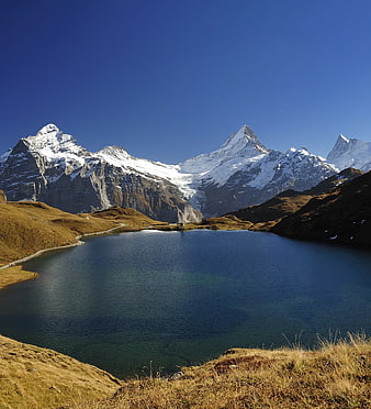 Alpine lake with snow-capped mountains and clear blue sky