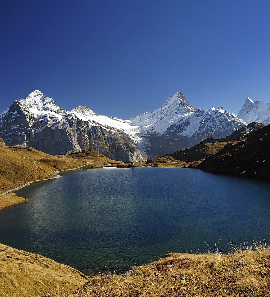 Alpine lake with snow-capped mountains and clear blue sky