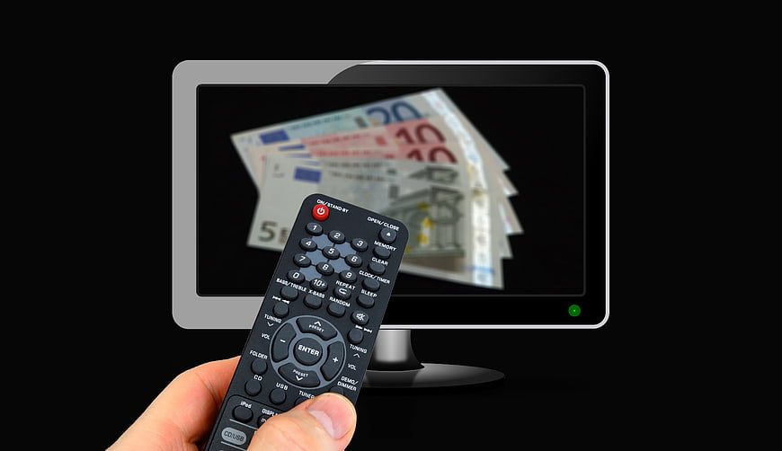 Hand holding remote control pointing at TV with Euro banknotes