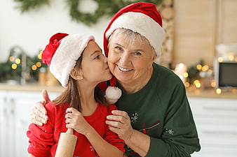 Grandmother and granddaughter kissing in Christmas hats
