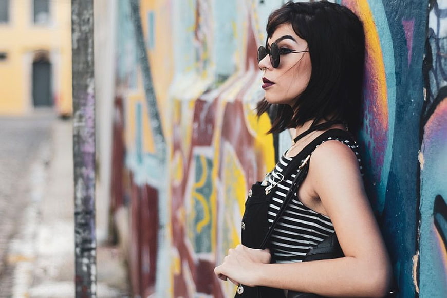 Stylish Woman in Sunglasses Against Colorful Graffiti Wall