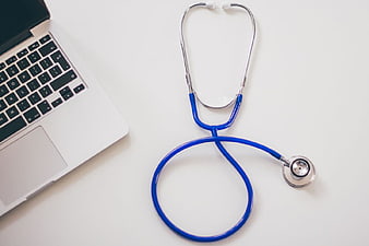 Blue Stethoscope and Laptop on White Desk
