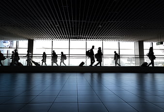 Silhouettes of travelers walking through modern airport terminal
