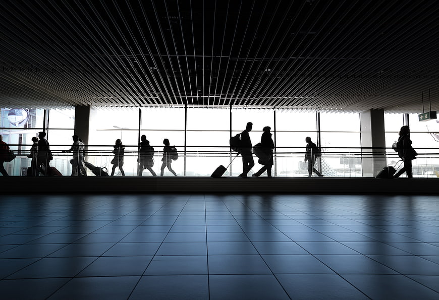 Silhouettes of travelers walking through modern airport terminal