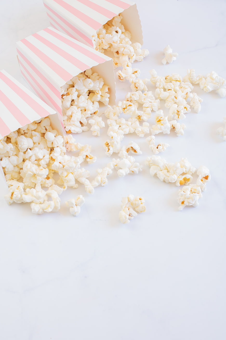 Pink striped popcorn boxes spilling onto white marble surface