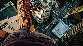First-person view of feet on high-rise ledge overlooking city