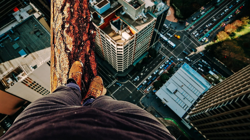 First-person view of feet on high-rise ledge overlooking city