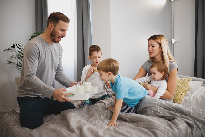 Happy family eating breakfast in bed together