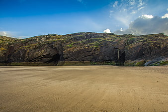 Sandy Beach with Rocky Cliffs and Blue Sky