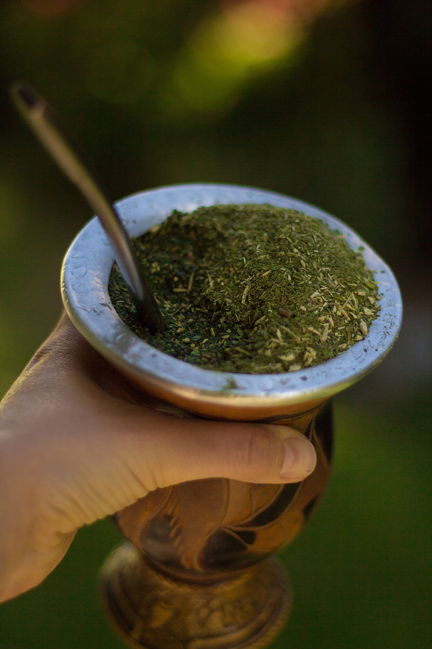 Hand holding traditional mate gourd with yerba mate and bombilla