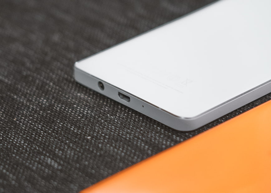 Close-up of white smartphone bottom edge on textured surface