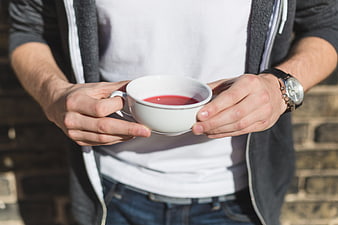 Man holding white cup with red tea outdoors