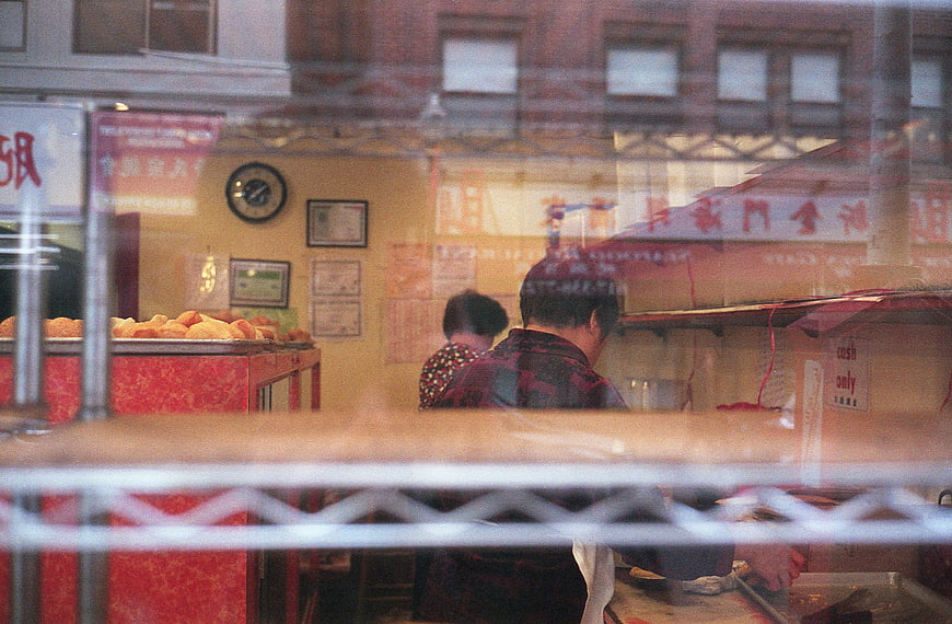 Reflections of Asian Bakery Workers Through Glass Window