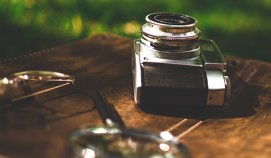 Vintage Camera and Glasses on Leather Surface