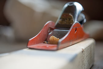 Close-up of red hand plane on wood with shavings