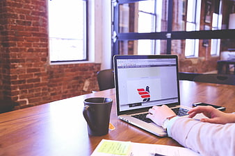 Person working on laptop in modern office with coffee