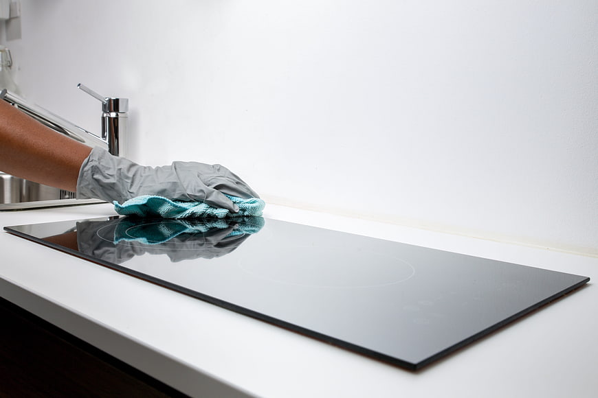 Hand in glove cleaning modern black glass cooktop