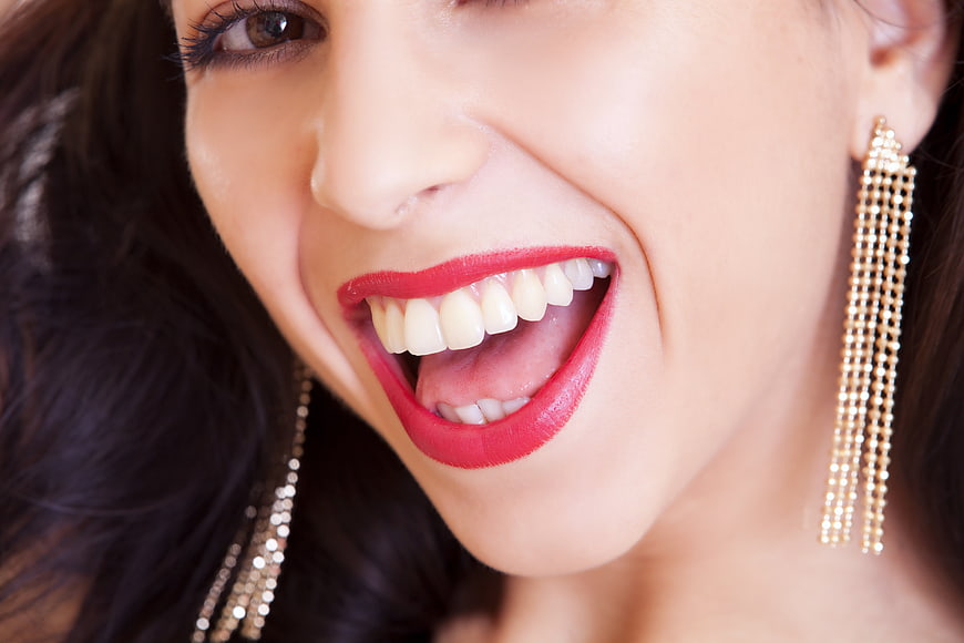 Close-up of woman laughing with red lipstick and gold earrings