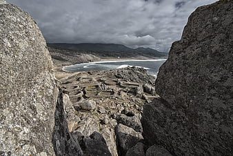 Ancient stone ruins on rocky coastal landscape with ocean view