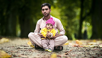 Father and Baby Sitting in Park with Autumn Leaves