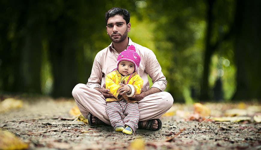 Father and Baby Sitting in Park with Autumn Leaves