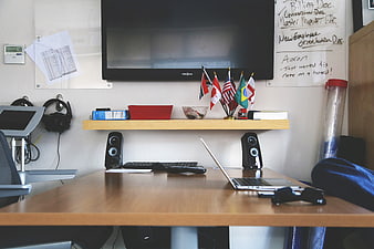 Modern office workspace with laptop, flags, and whiteboard