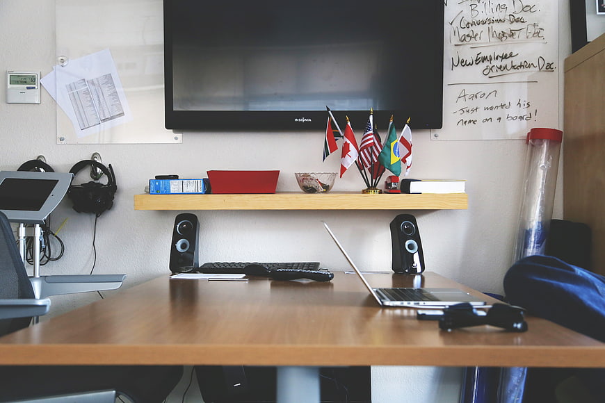 Modern office workspace with laptop, flags, and whiteboard