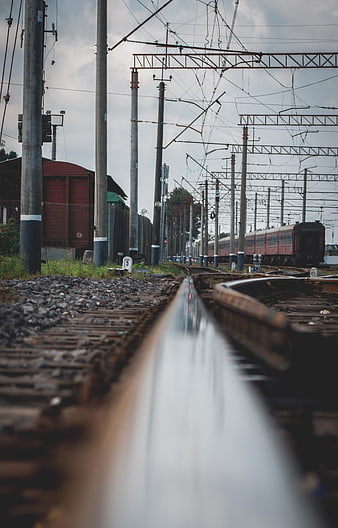 Low angle view of railway tracks with red train in background