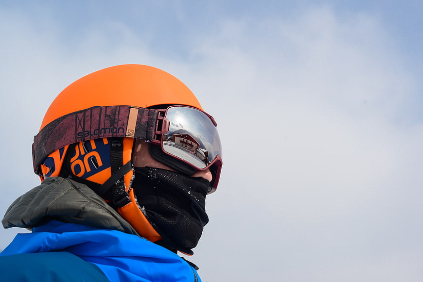 Close-up of skier in orange helmet and goggles against sky