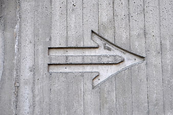 Concrete arrow sign engraved on gray cement wall