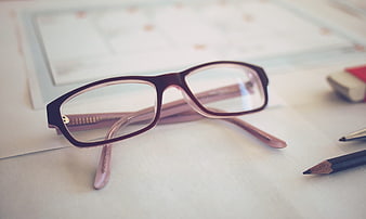 Close-up of eyeglasses on desk with office supplies
