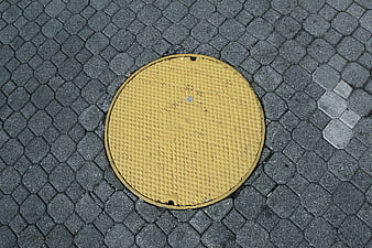 Yellow Manhole Cover on Gray Paved Street Texture