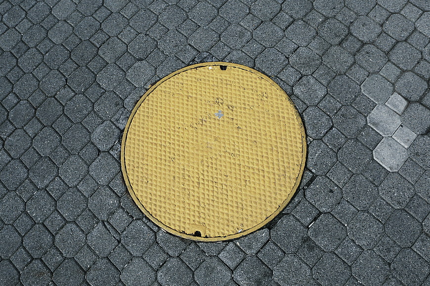 Yellow Manhole Cover on Gray Paved Street Texture