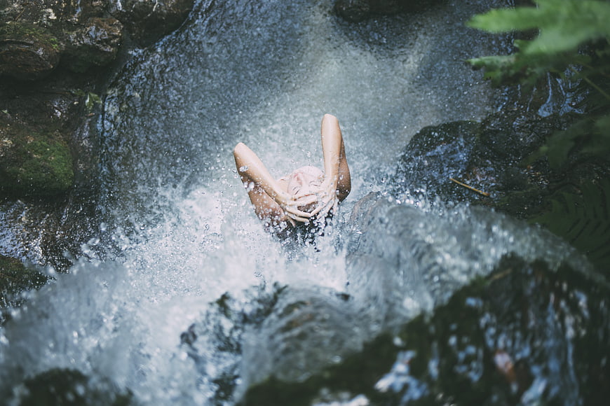 Woman bathing in a natural waterfall stream