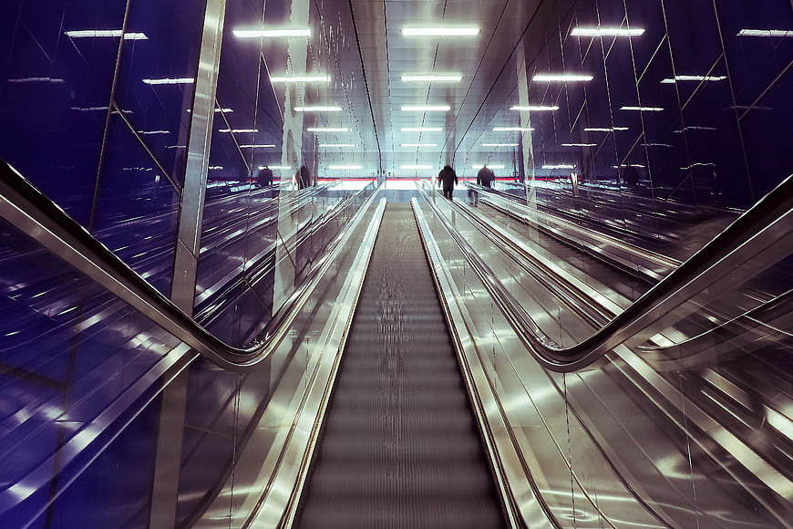 Modern Metro Station Escalator With Blue Reflections And Urban Architecture