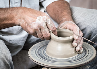 Potter shaping clay vase on spinning wheel