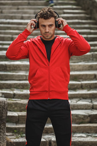 Man in Red Hoodie Listening to Music on Headphones