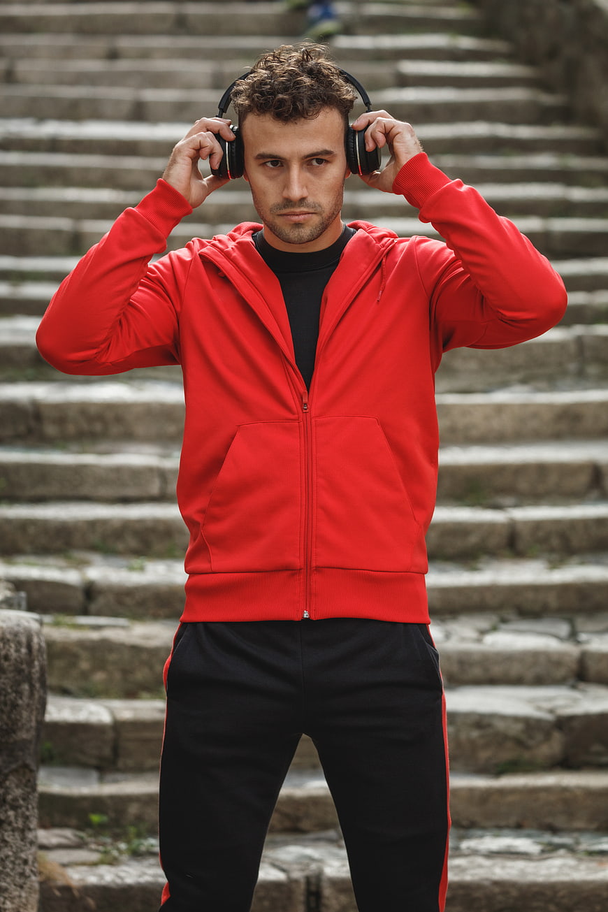 Man in Red Hoodie Listening to Music on Headphones