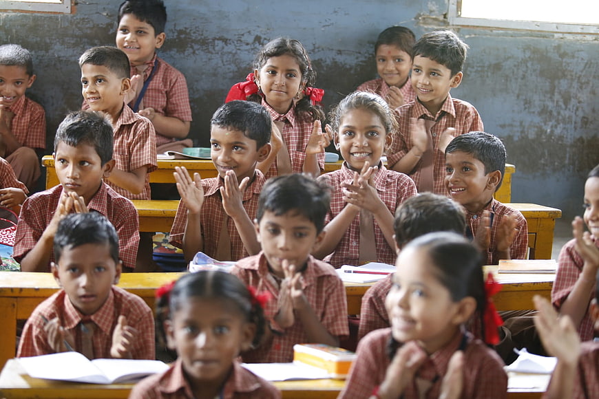 Group of smiling school children clapping in classroom