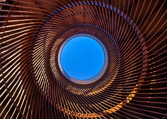 Spiral wooden architecture looking up at blue sky