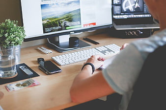 Man working at desk with computer and smartphone