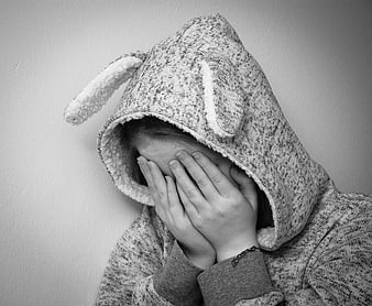 Sad Teenager in Bunny Hoodie Covering Face in Black and White