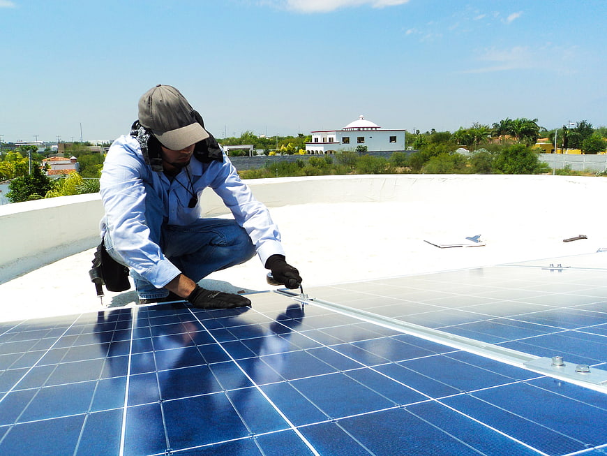 Technician Installing Solar Panels On Residential Rooftop