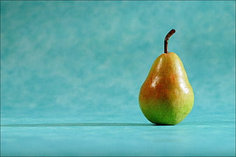 Single ripe pear on textured turquoise background