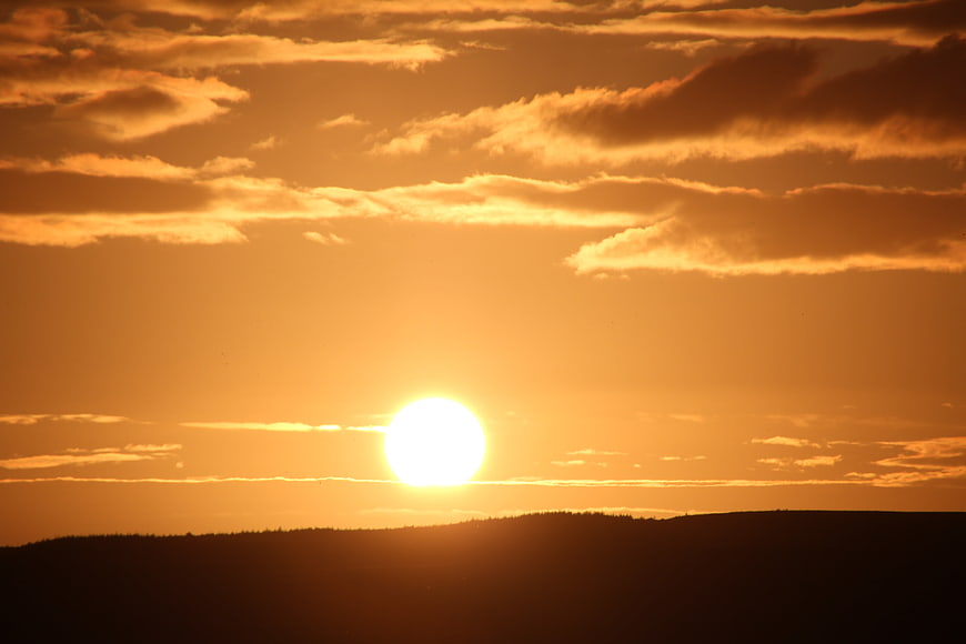 Golden sunset over rolling hills with dramatic clouds