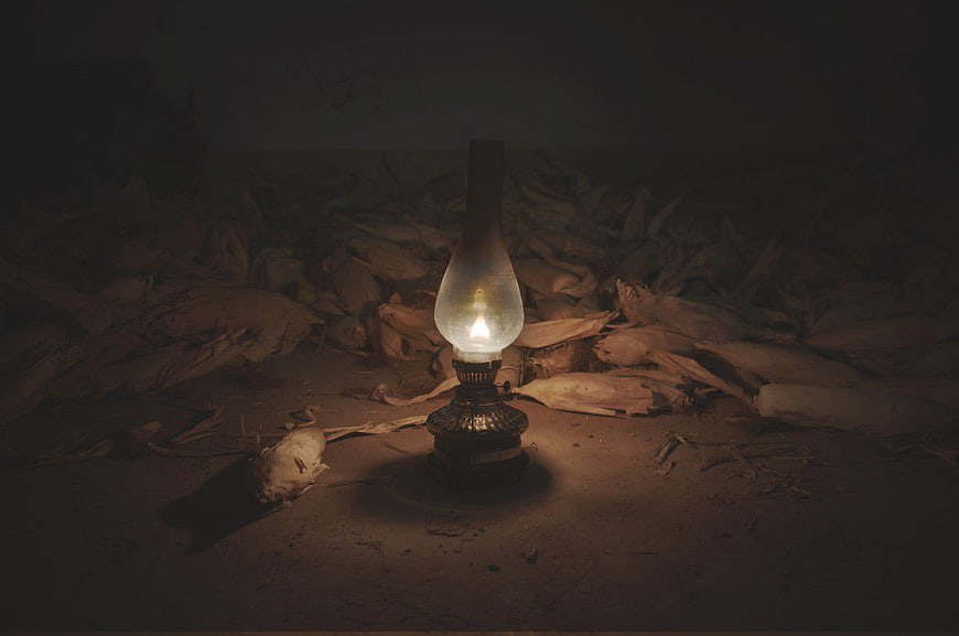 Vintage Oil Lamp Illuminating Dark Room with Wood Shavings