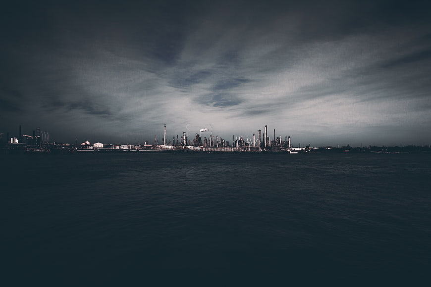 Dark Industrial Refinery Skyline Over Water