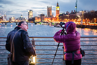 Photographer capturing London skyline at dusk from riverbank