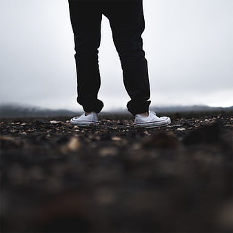Low angle shot of white sneakers on rocky ground